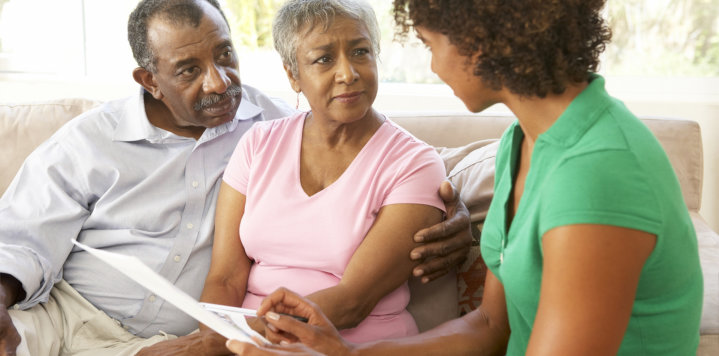 elderly couple talking to a woman at home